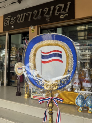 ตาลปัตรลายธงชาติไทย  มีแบบผ้าไหม และ ตาลปัตรจักสาน   ปักชื่อเพิ่มได้ 2